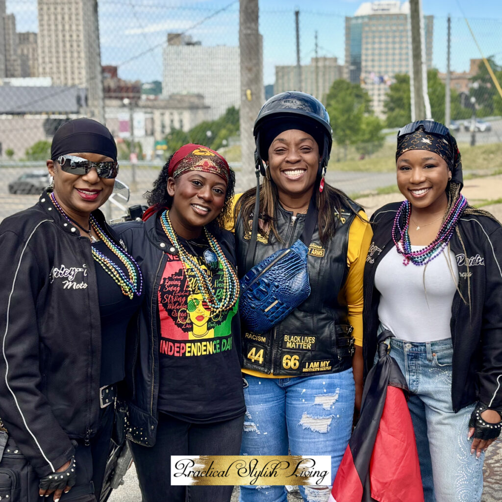 Buffalo Soldiers This image showcases four women posing confidently together at Juneteenth Celebration, radiating a sense of community and shared passion. Members of The Buffalo Soldiers motorcycle group, as indicated by their attire and the presence of a motorcycle in the background.