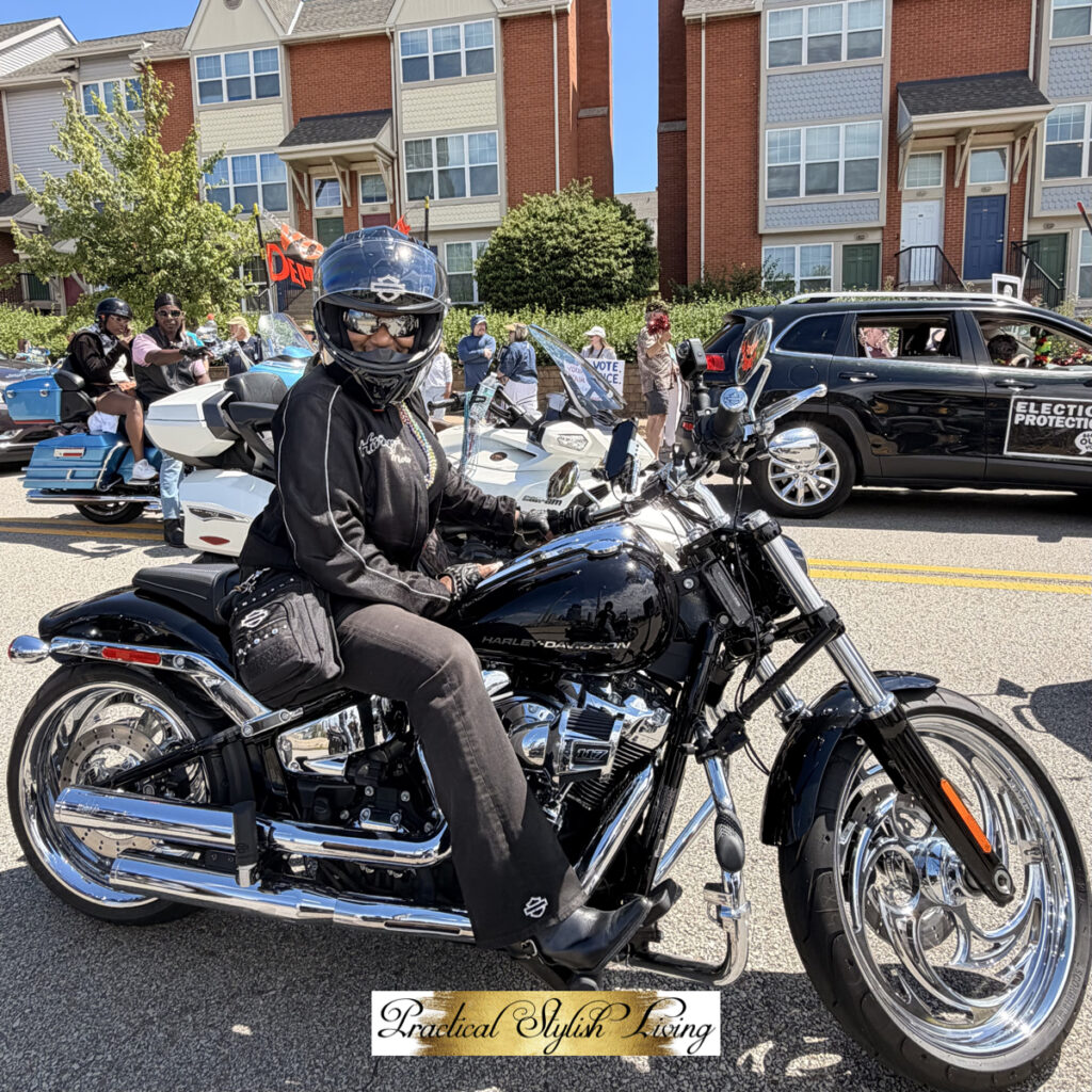 Kimberly R. Jones sitting on a Harley-Davidson motorcycle with a striking 21-inch chrome front wheel and a classic Milwaukee-Eight V-twin engine.